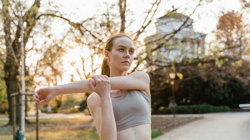 Femme faisant des étirements dehors dans un parc